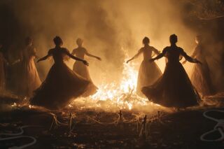 Women in silhouette dancing around a bonfire