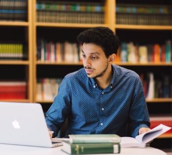 A lecturer browsing books and interacting with a laptop