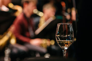 Wine glass in foreground with jazz band out of focus in background.