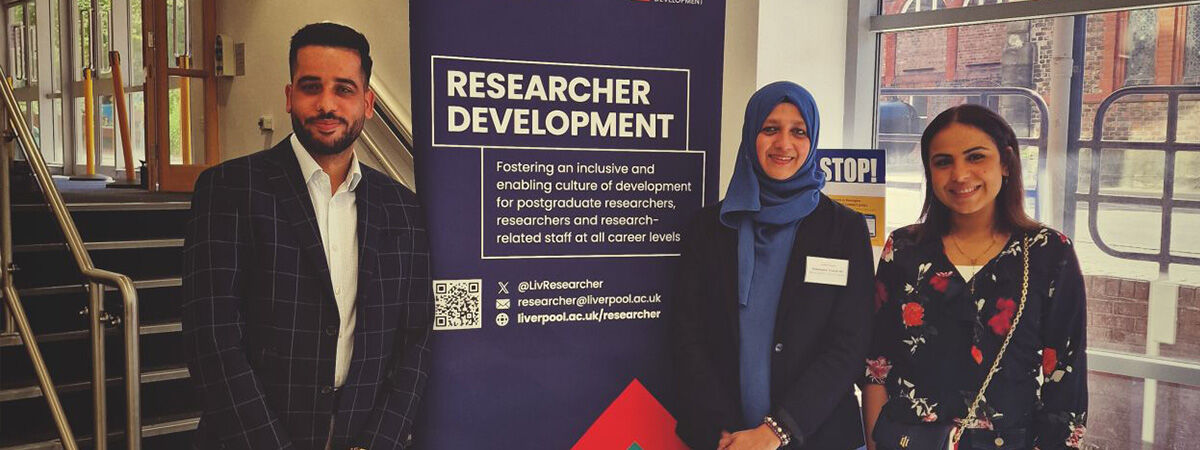 PGR Conference Group Smiling with Sign Saying Research Conference