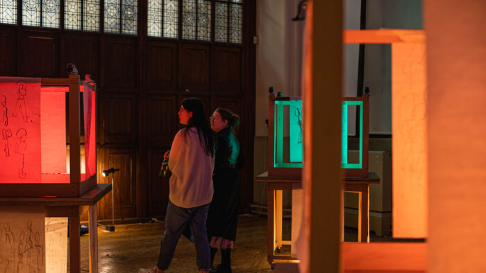 Two individuals observing sculptures in the School of Art gallery.