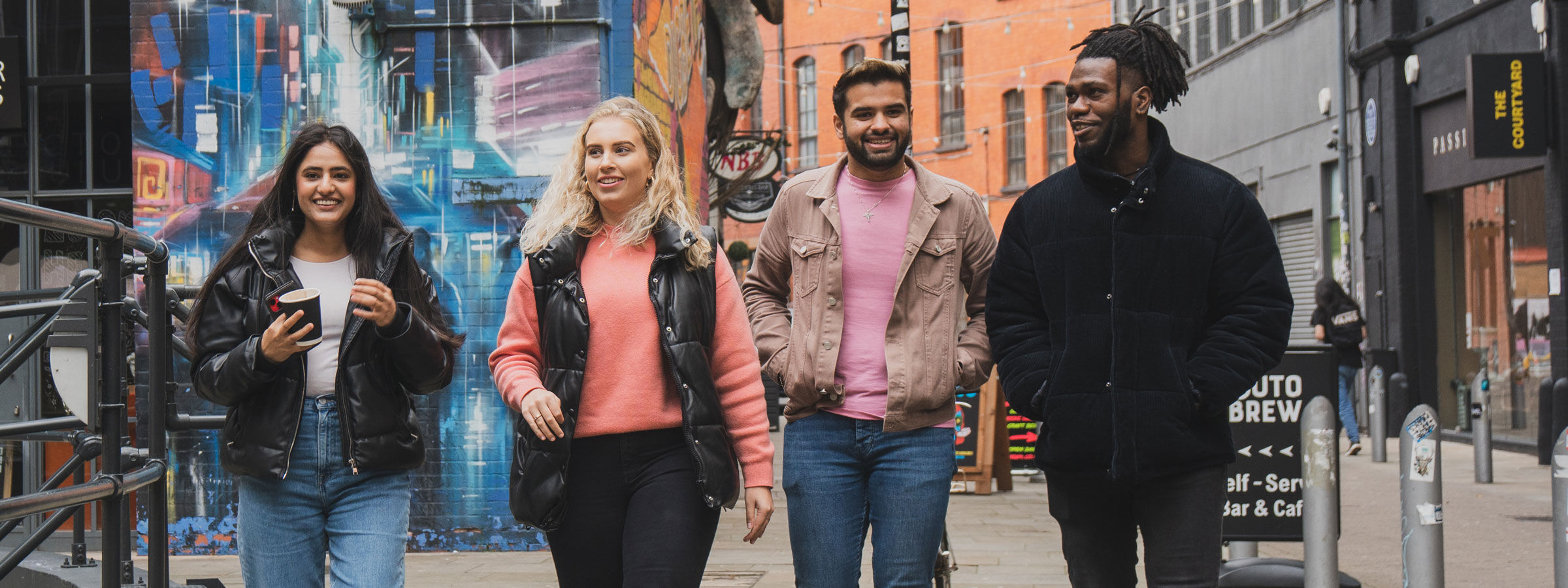Four students talk and laugh as they walk through Digbeth, an area in Birmingham city centre