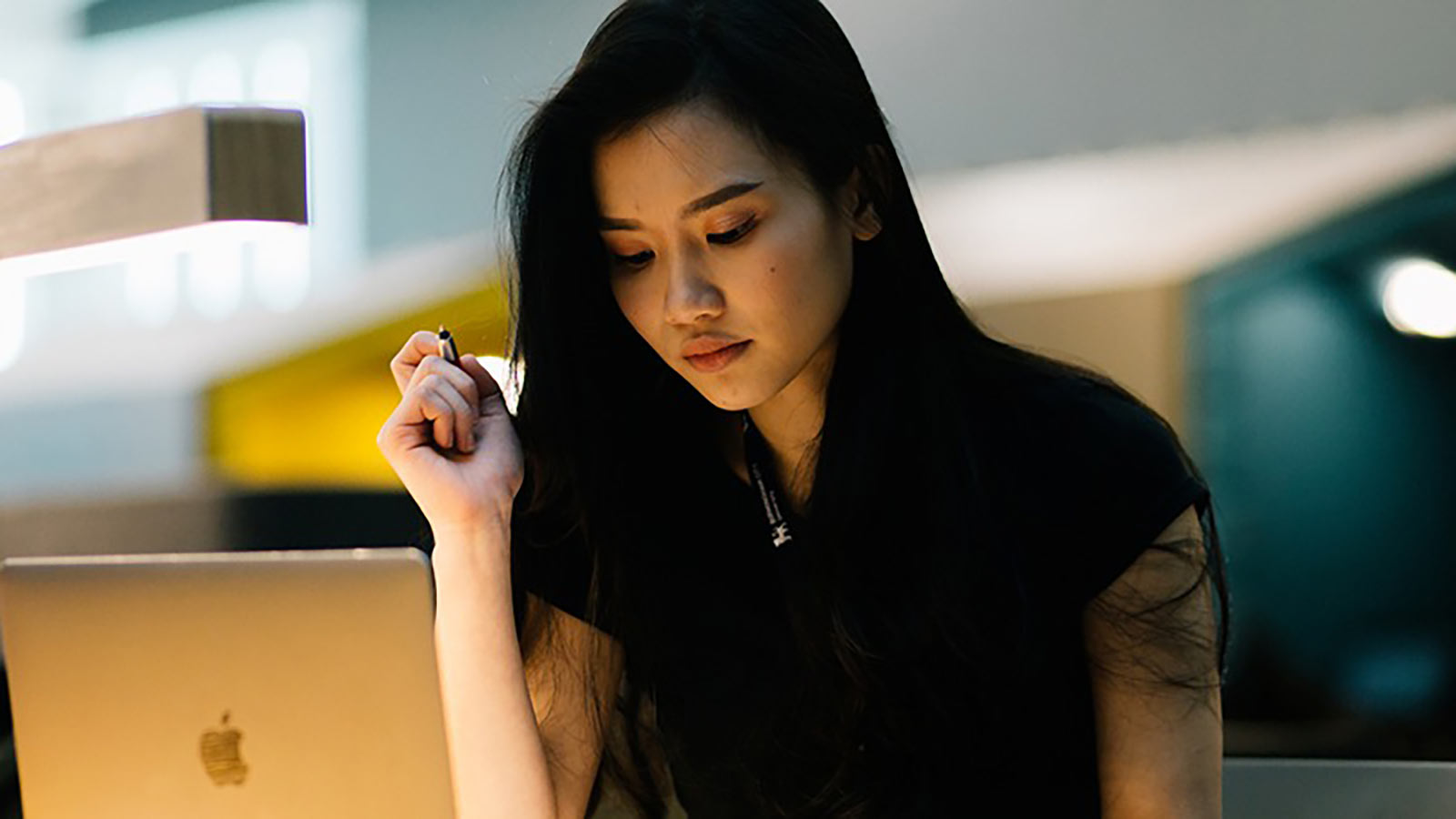 Student working on laptop and holding a pen