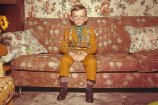 Small boy sitting in a lavishly decorated room, early 20th century