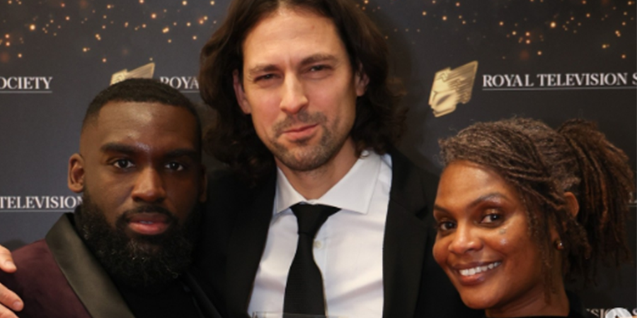Two men and one woman stood smiling at an awards ceremony