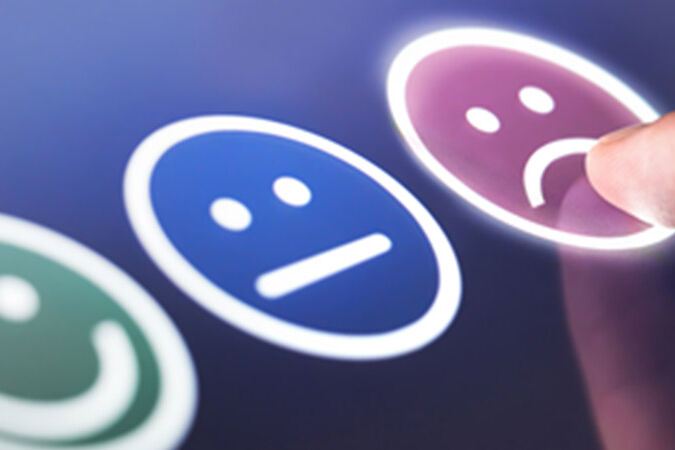 Three emojis - happy, middling and sad - on an iPad.