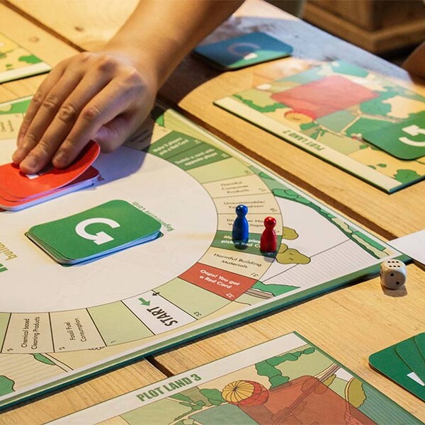 A person playing a board game called "Regenerate!" Game board has circular design with a green "G" in centre, related to sustainability
