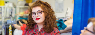 Student nurse sat next to model hospital bed with her walking stick.
