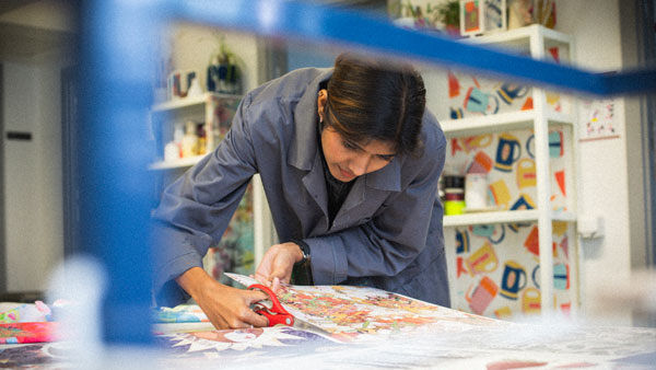 An art student cutting some art work with scissors