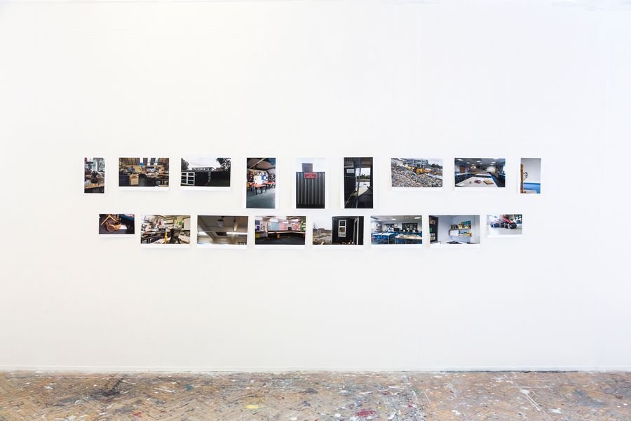 A series of small photographs arranged in a horizontal line on a white gallery wall