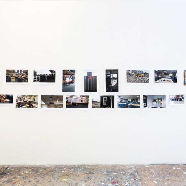 A series of small photographs arranged in a horizontal line on a white gallery wall