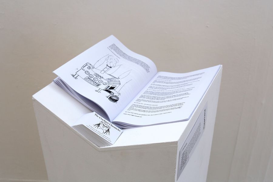Open book with black and white illustrations displayed on a white, geometric pedestal against a neutral background