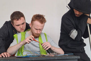 Three male RBC acting students in a scene with wiring