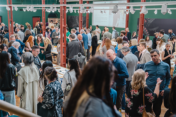 A room full of people visiting an exhibition or fair