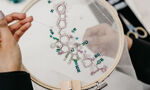 A student embroidering a pattern in blue thread