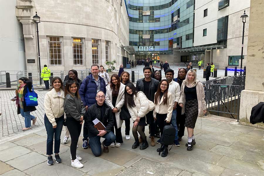 Students and lecturer stood smiling outside BBC building