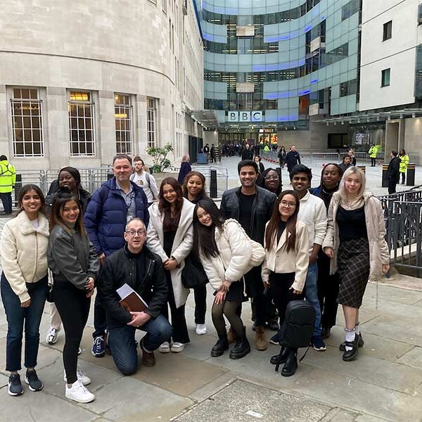 Students and lecturer stood smiling outside BBC building