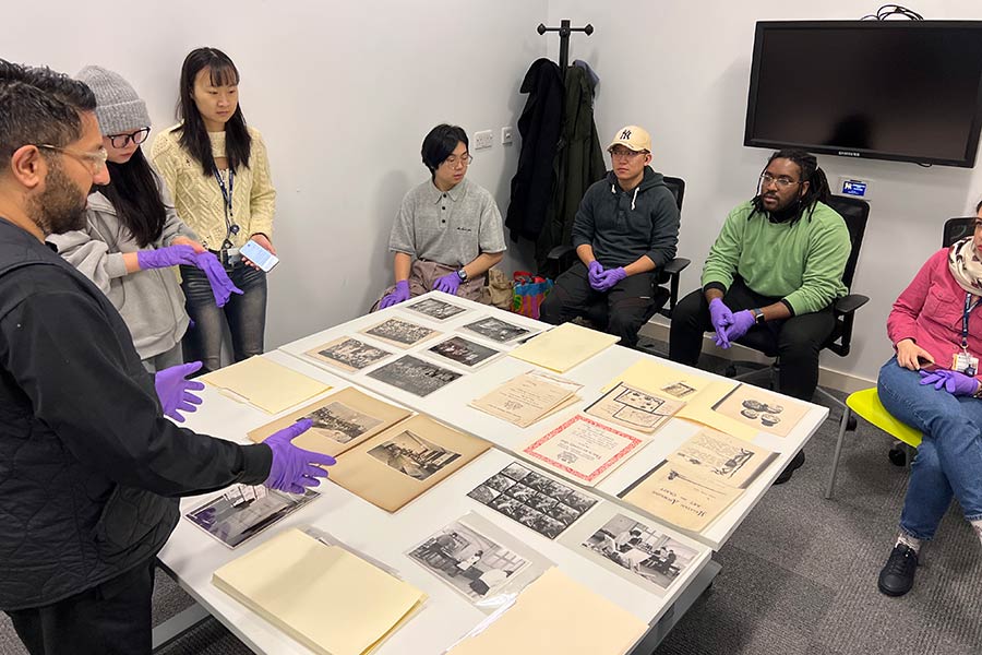 People stood round table looking at a variety of images and papers from an archive