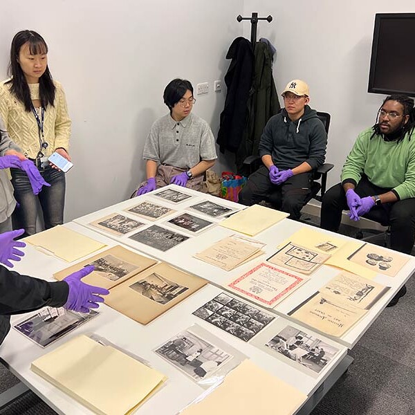 People stood round table looking at a variety of images and papers from an archive