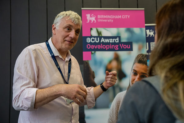 A staff member talks to a student about the BCU award
