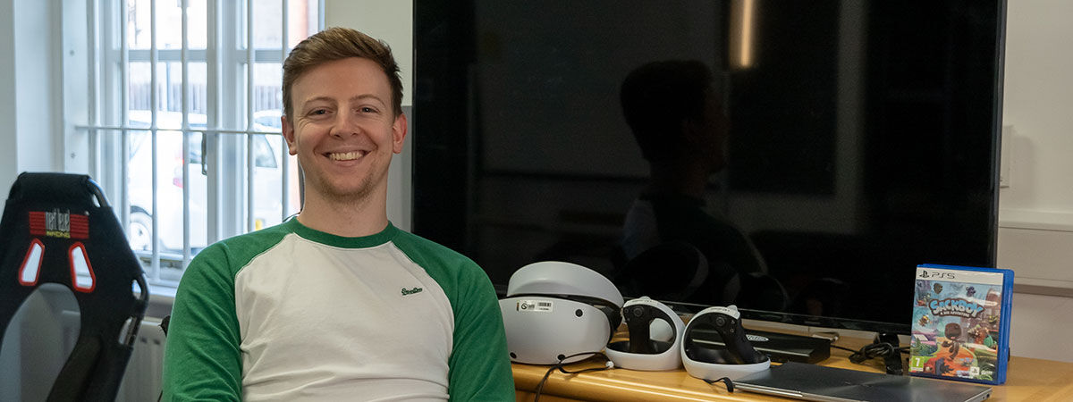 Benjamin Culff sits in front of a TV and Virtual Reality equipment