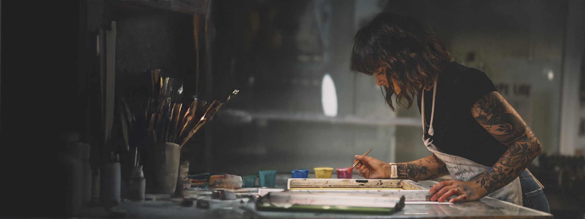 A student is using paints to create an artistic piece in a well equipped studio.