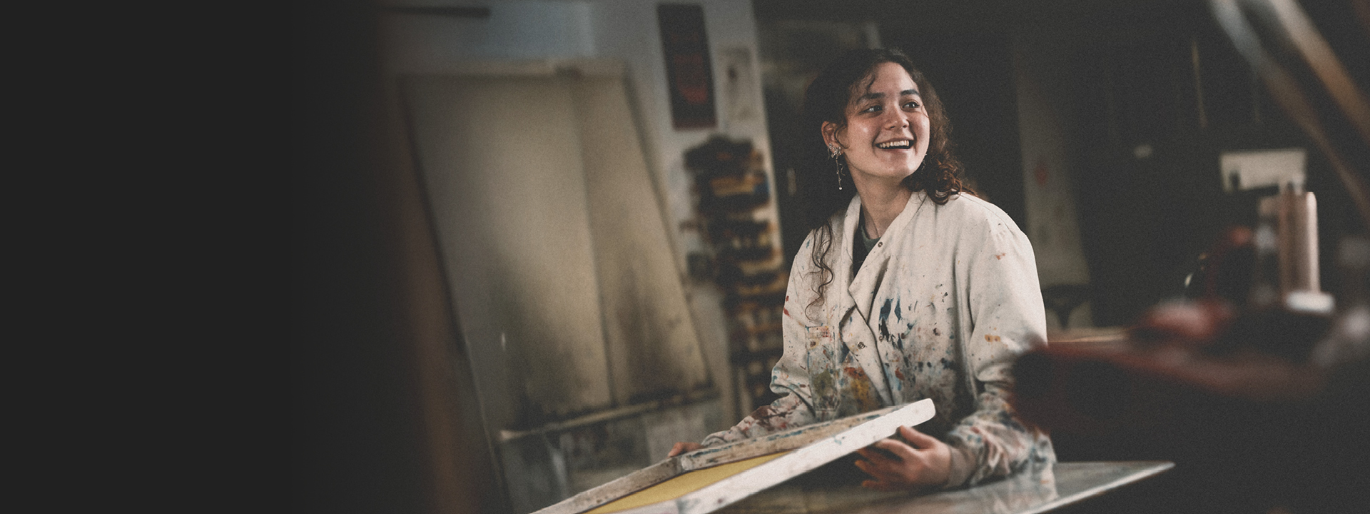 A student is using paints to create an artistic piece in a well equipped studio.