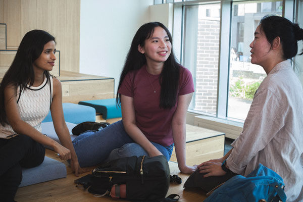 Three students chat on a sofa