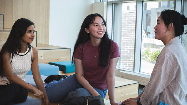 Three students chat on a sofa