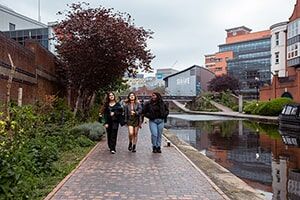 Students enjoying a walk along the canal surrounded by city buildings and trees
