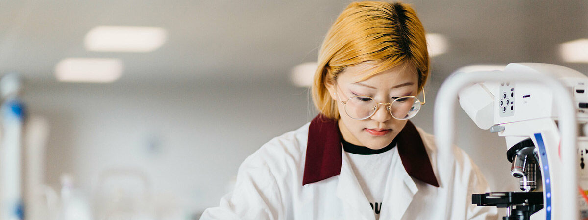 A student in a lab using a microscope