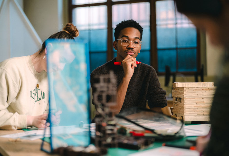 A student works in a group, he looks thoughtfully at the work on the table