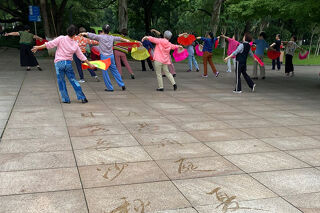 People holding flags in a park with Chinese writing on the floor