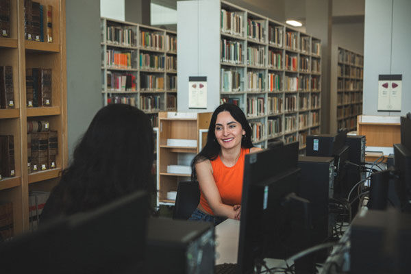 Two students sit happily at computers