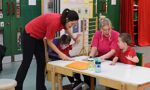 Two teachers interacting with two students, who are sat at a table in a classroom