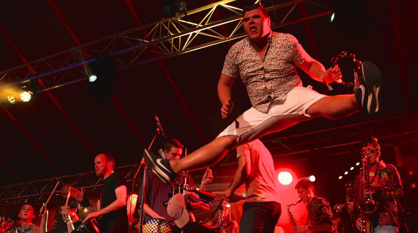 Member of conservatoire folk performer on stage whilst jumping in air