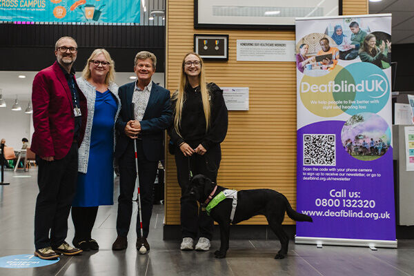 Two women and two men stood together with a guide dog and a sign reading Deafblind UK Centre 