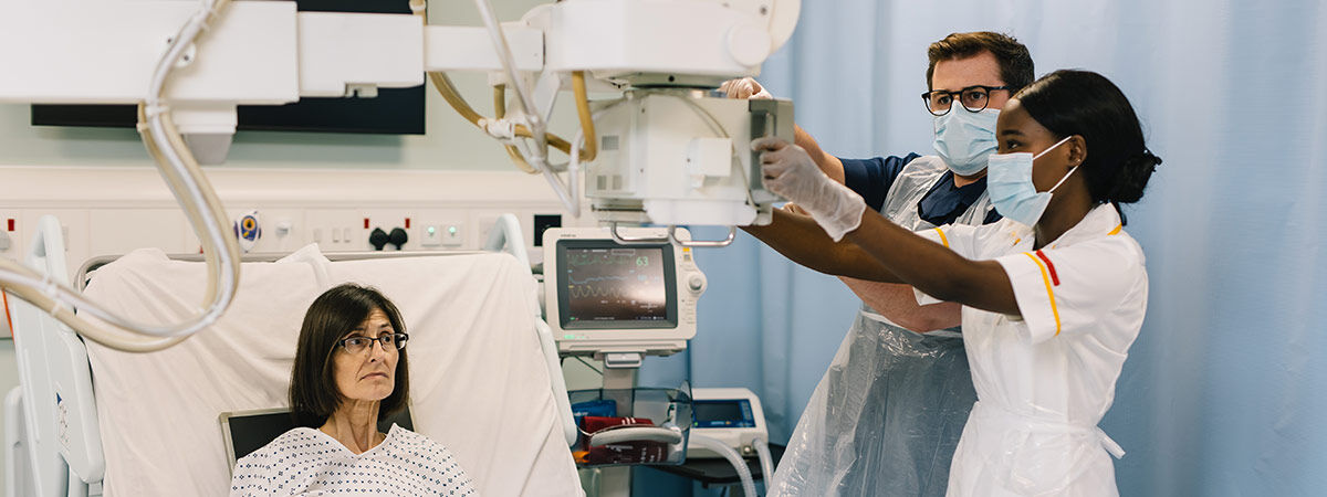 Patient in bed with teacher and student using radiography machine