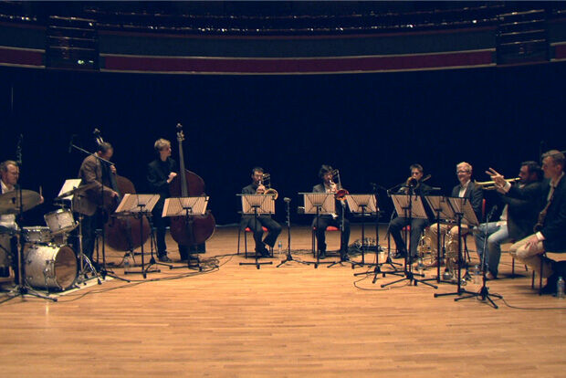 Nine musicians seated on stage