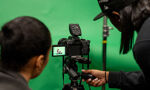 Students' framing up a camera shot against a green screen background