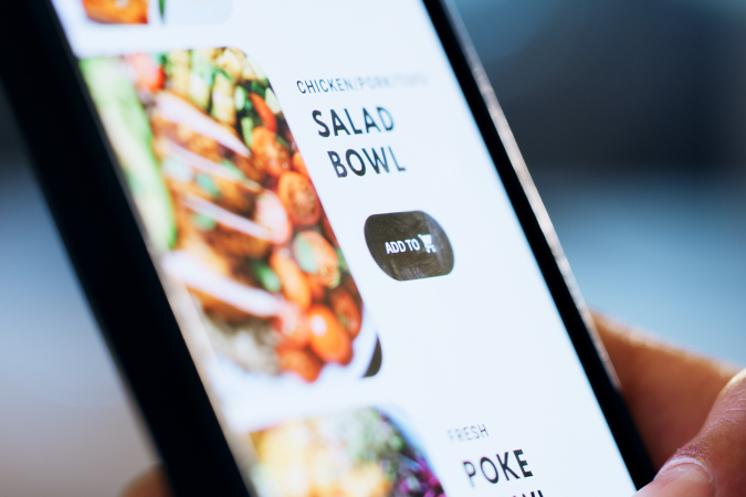 Image of finger scrolling food delivery app on phone.