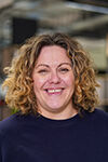 The image shows a woman with curly hair smiling.