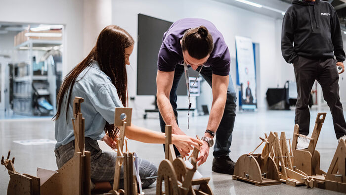 An image of a group of engineering students whose projects revolved around mini trebuchets that were tasked with firing projectiles.