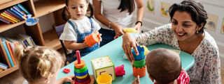 An early years professional helps young children during a class.