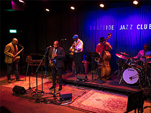 A group of musicians playing jazz in Eastside Jazz Club, the lighting is dark and atmospheric 