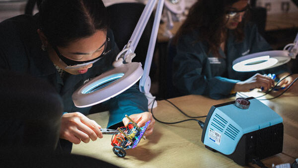 A student works with electrical wires under a spotlight