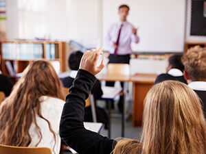 School pupil in lesson raising hand