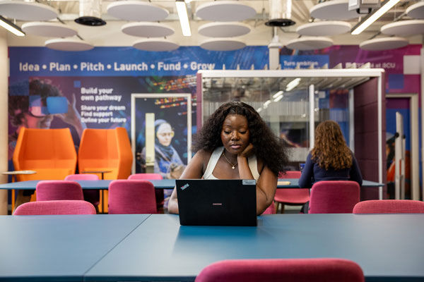 A student hotdesking, working on a laptop, in BCU's Enterprise Hub