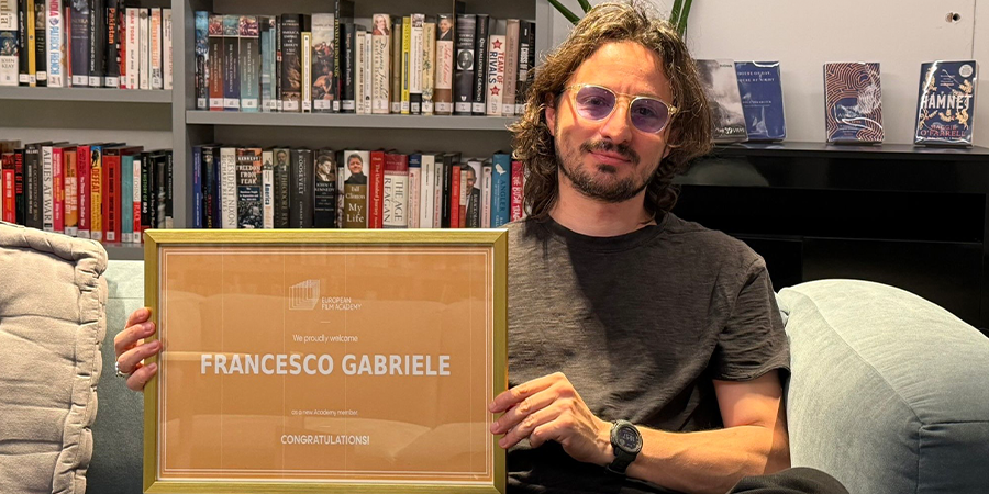Francesco holding up his certificate of his film academy membership 