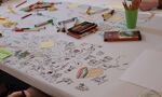 Picture of a table which has drawings in marker pen engrained, with coloured marker pens surrounding it